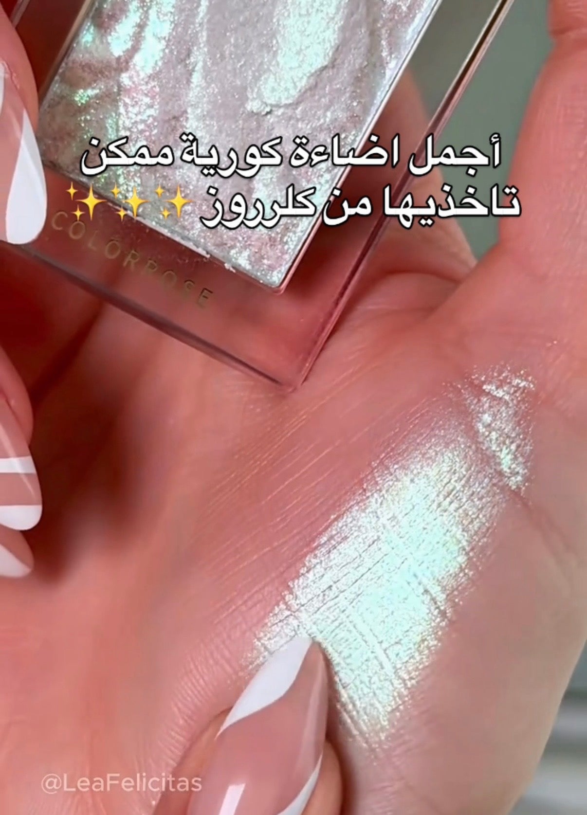 Hand holding a cosmetic product with glittery texture, showing color swatch on skin.